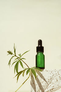 Cbd oil in a bottle on a geometric stand with leaf of marijuana, cannabis