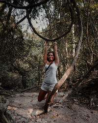 Full length of woman handing on tree in forest