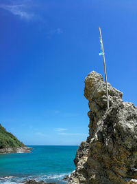 Rock formation on sea against blue sky