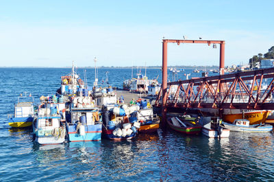 Boats moored at harbor against sky