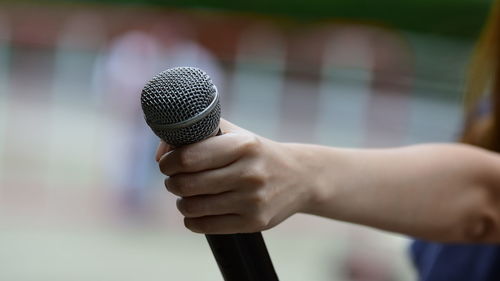 Cropped hand of woman holding microphone