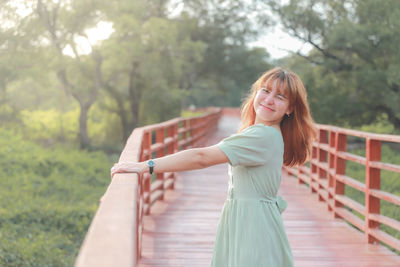 Young woman standing against trees