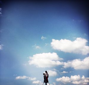 Low angle view of woman standing against cloudy sky