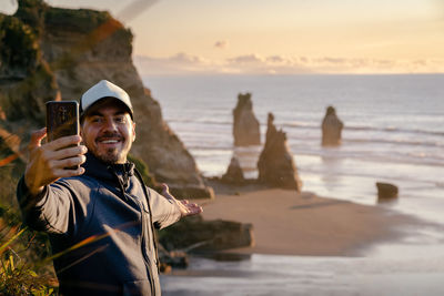 Portrait of smiling man photographing sea