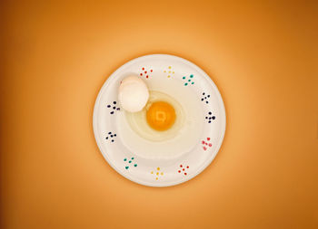 Directly above shot of raw chicken egg on white plate