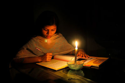 Mid adult woman with light painting on table in darkroom