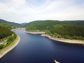 Scenic view of river by mountains against sky