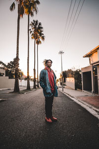 Full length portrait of young man standing on road against sky