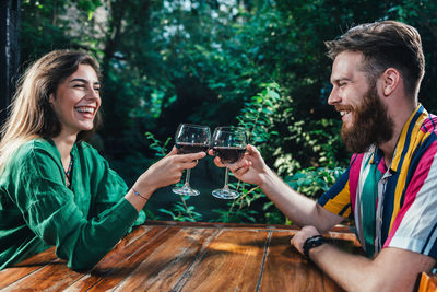 Smiling young couple toasting wineglasses while sitting at table