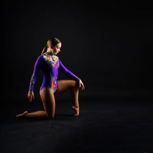 Portrait of young woman standing against black background