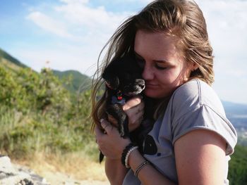 Midsection of woman holding dog against sky