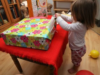 Full length of cute girl opening gift at home