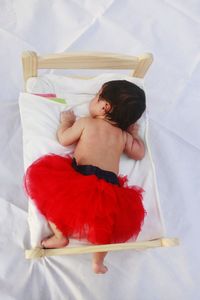 Rear view of baby girl sleeping on bed at home