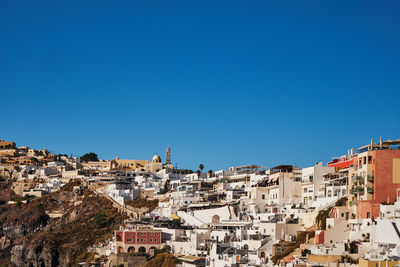Buildings in city against clear blue sky
