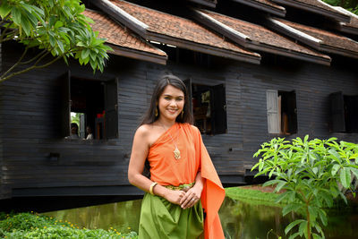 Smiling woman in traditional clothing standing outside temple