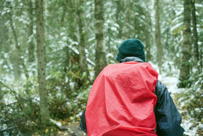 Rear view of backpack man hiking in forest during winter