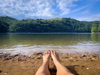 Personal perspective of female tanned feet resting near the lake in summer