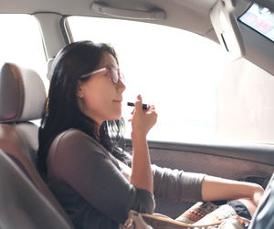 Young woman applying lipstick in car