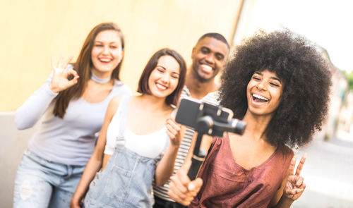 Cheerful friends taking selfie with mobile phone in city