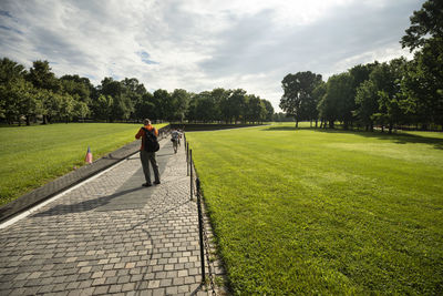 Rear view of man walking on footpath against sky