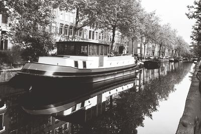 Boat moored in canal by trees in city