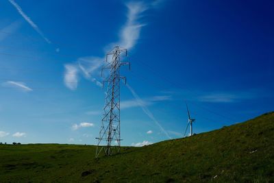 Low angle view of electricity pylon against blue sky