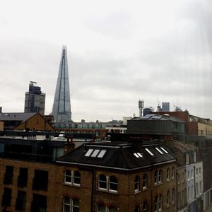 Buildings in city against cloudy sky