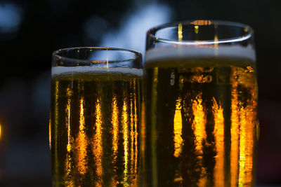 Glasses of beer with blurred lights on background