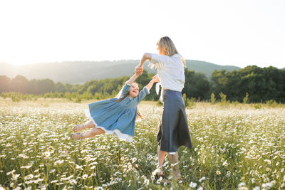 Woman spinning girl in field