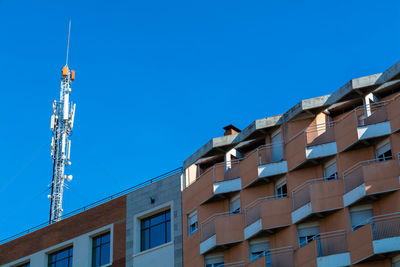 Low angle view of communications tower on building against clear sky