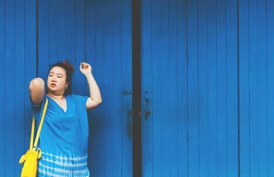 Woman standing against blue wooden door