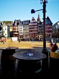 People sitting by buildings in city against sky