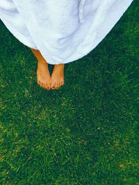 Low section of woman wearing towel standing on grass