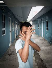 Portrait of young man standing on covered walkway