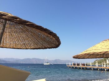 Wooden parasols at beach against clear blue sky