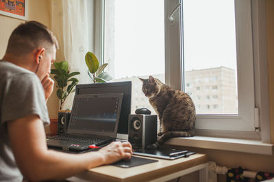 Side view of man using laptop on table at home