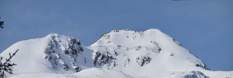 Low angle view of snow covered mountain against blue sky