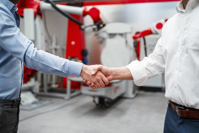 Male entrepreneurs shaking hands in factory