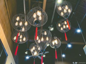 Low angle view of illuminated pendant lights hanging from ceiling at restaurant