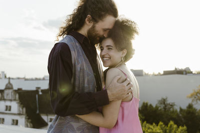 Smiling man embracing woman on rooftop