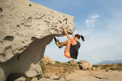 Full length of woman climbing rock against sky