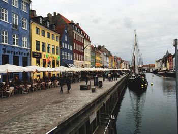 Boats in canal amidst buildings in city against sky