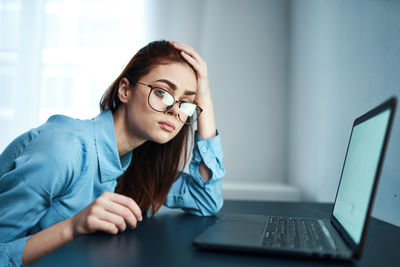 Portrait of young woman sitting at desk in office