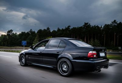 Cars on road against cloudy sky