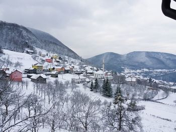 Houses by buildings against sky during winter