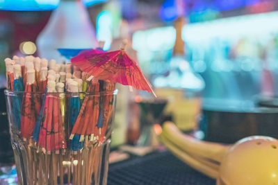 Close-up of drink umbrellas in glass on bar counter at nightclub