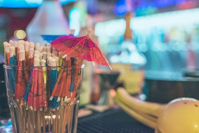 Close-up of drink umbrellas in glass on bar counter at nightclub