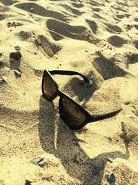 High angle view of sunglasses on sand at beach