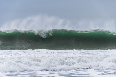 Waves rushing towards sea against sky