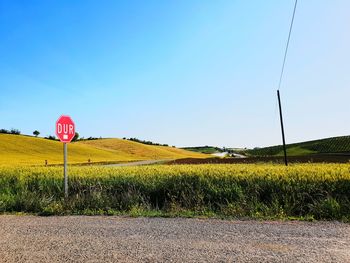 Road sign on field against clear sky